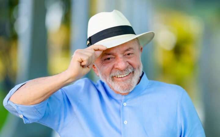Lula, de camisa azul e chapéu panamá, sorri e segura a aba do chapéu com uma das mãos, no Palácio da Alvorada