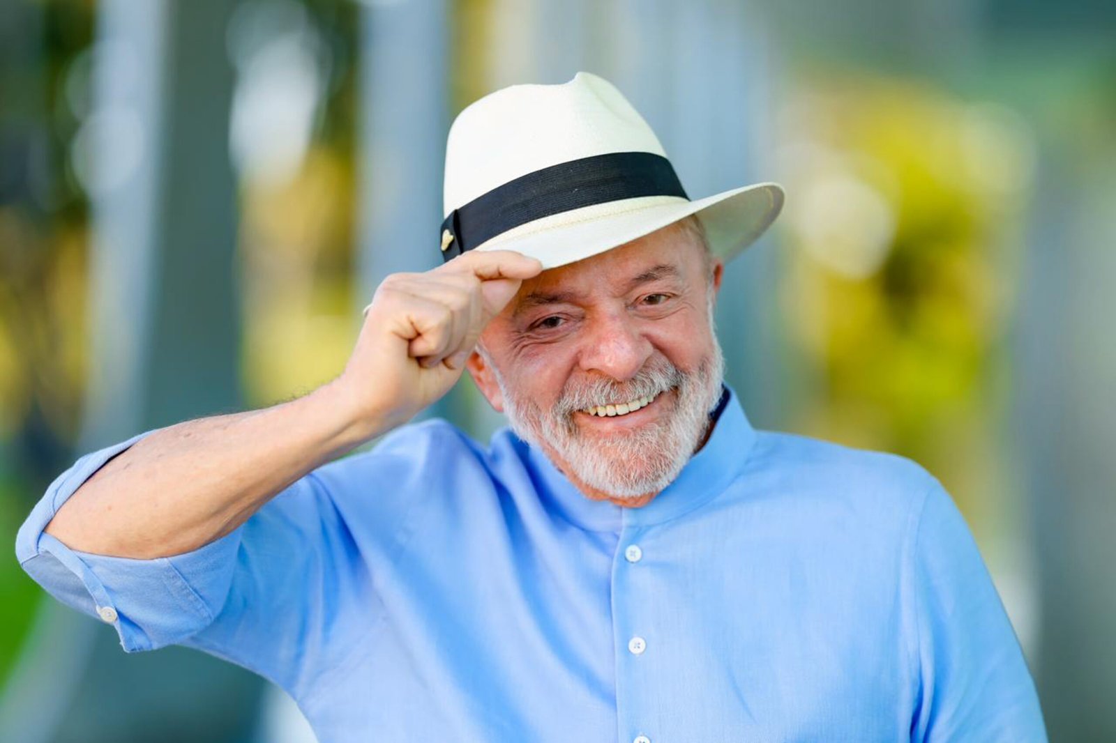 Lula, de camisa azul e chapéu panamá, sorri e segura a aba do chapéu com uma das mãos, no Palácio da Alvorada