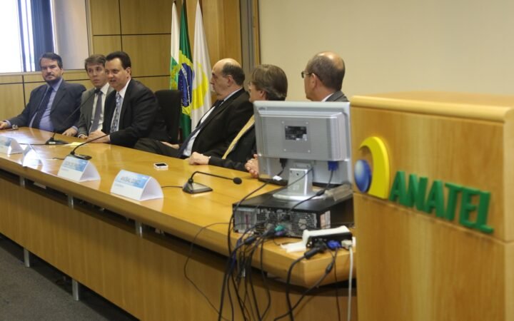 Mesa de reunião com o logotipo da Anatel e a bandeira do Brasil