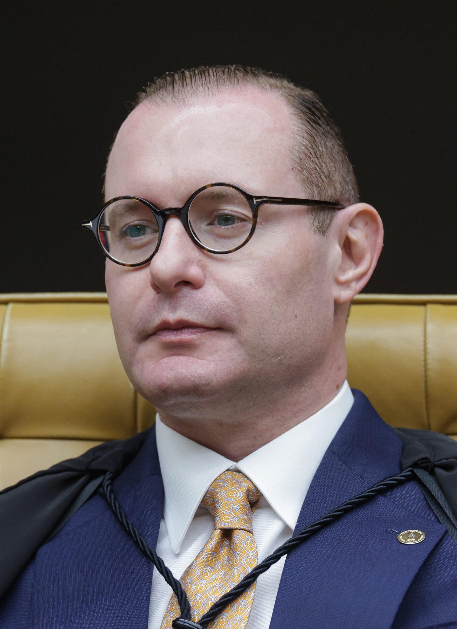 O ministro Cristiano Zanin, de óculos redondos e terno azul, sentado em sessão plenária do Supremo Tribunal Federal