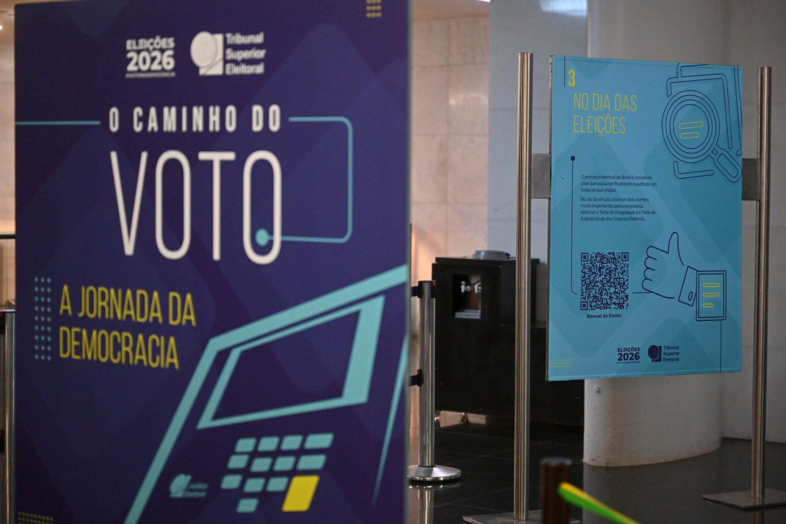 Painel da exposição 'O Caminho do Voto – a jornada da democracia', com a marca Eleições 2026 e a ilustração de uma urna eletrônica