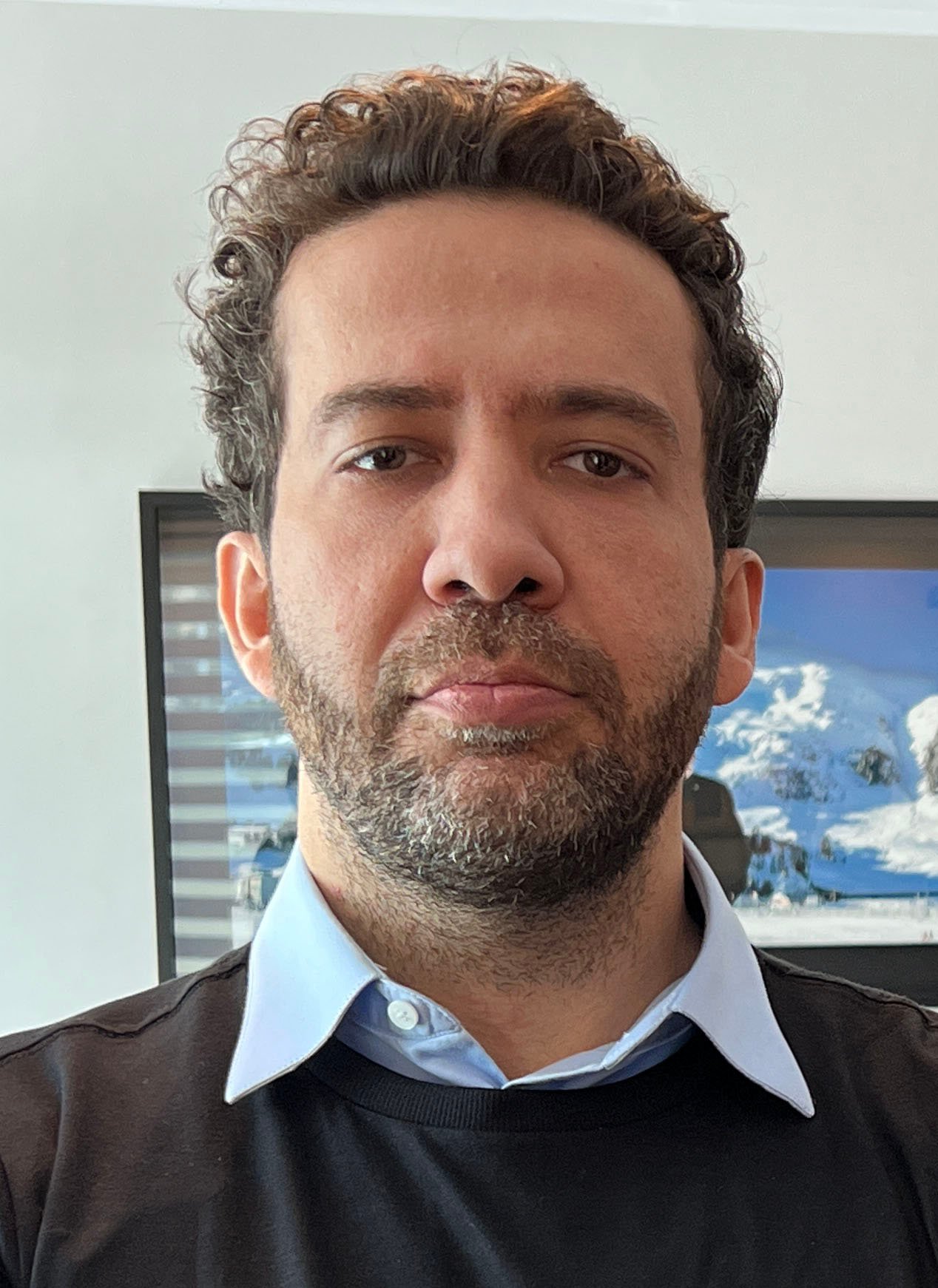 Retrato do deputado federal André Janones, de barba, camisa azul e suéter escuro