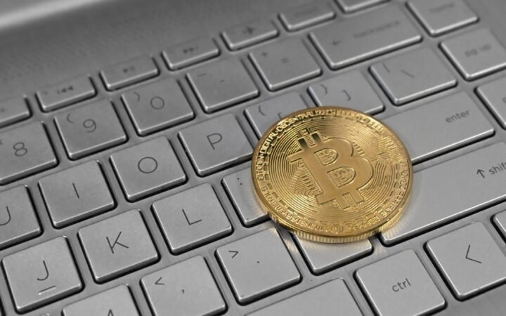 Moeda dourada com o símbolo do bitcoin sobre o teclado de um notebook