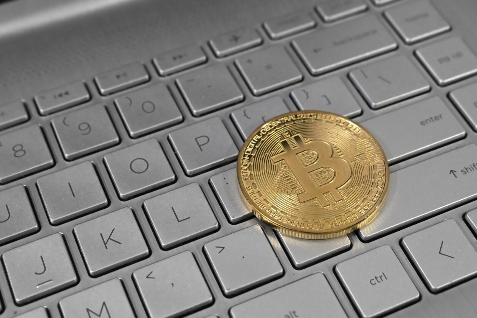 Moeda dourada com o símbolo do bitcoin sobre o teclado de um notebook