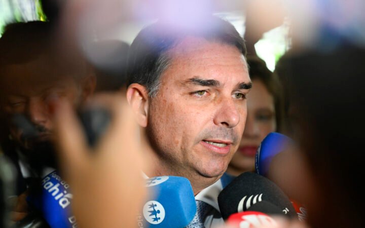 O senador Flávio Bolsonaro fala diante de microfones de emissoras de rádio e TV em entrevista no Senado