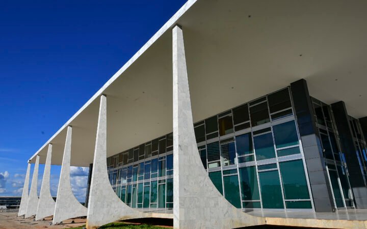 Fachada do edifício do Supremo Tribunal Federal, em Brasília, com colunas de mármore branco e vidro sob céu azul.