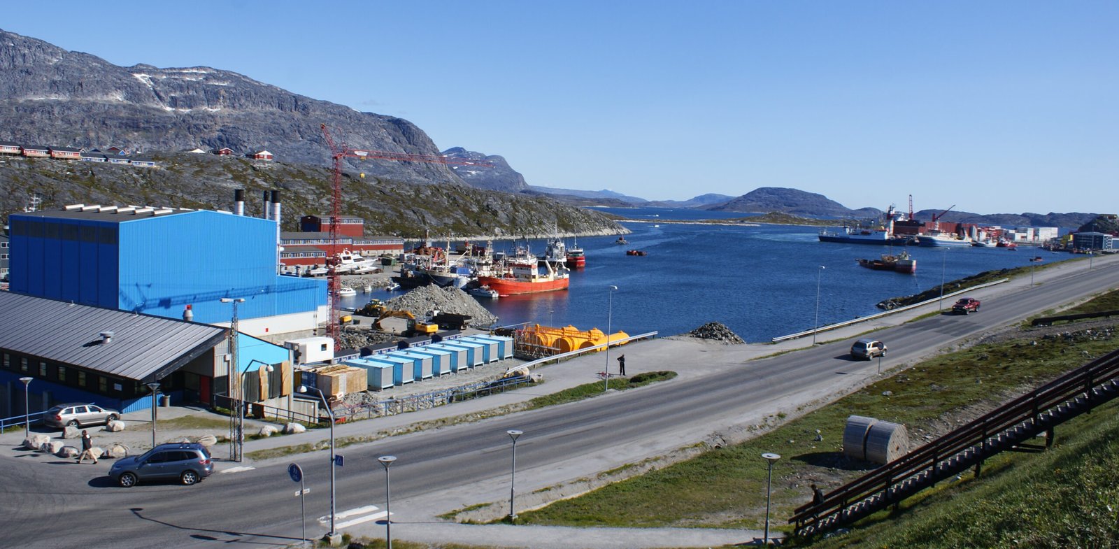 Porto de Nuuk, na Groenlândia, com navios, galpões e montanhas ao fundo