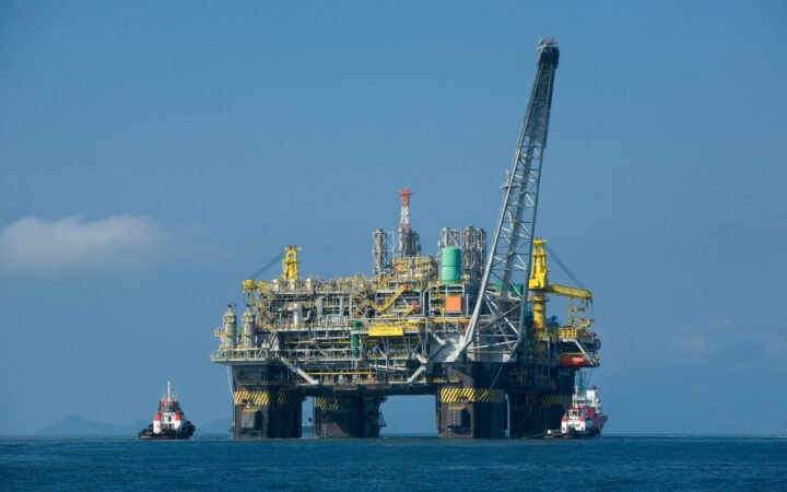Plataforma semissubmersível de petróleo P-51 no mar, com dois rebocadores