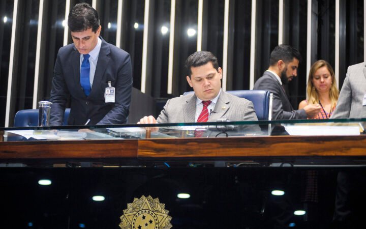 Davi Alcolumbre sentado à mesa diretora do Plenário do Senado, com assessores ao fundo e o brasão da República à frente