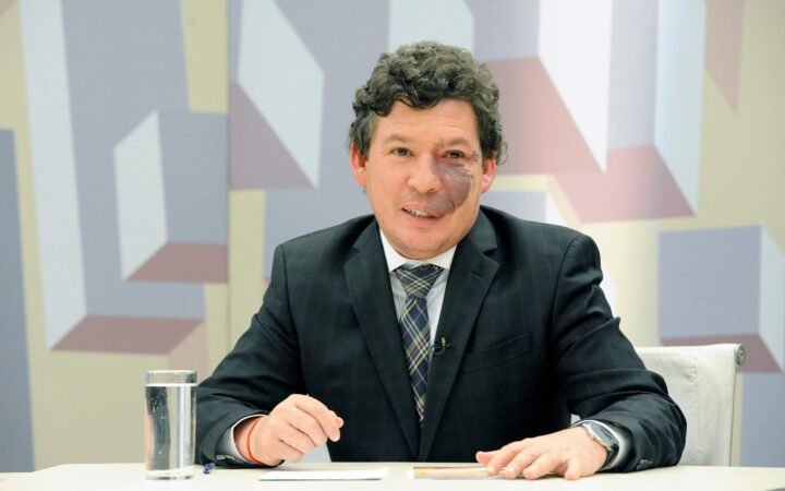 O deputado federal Reginaldo Lopes (PT-MG), sentado à mesa em estúdio da Câmara dos Deputados