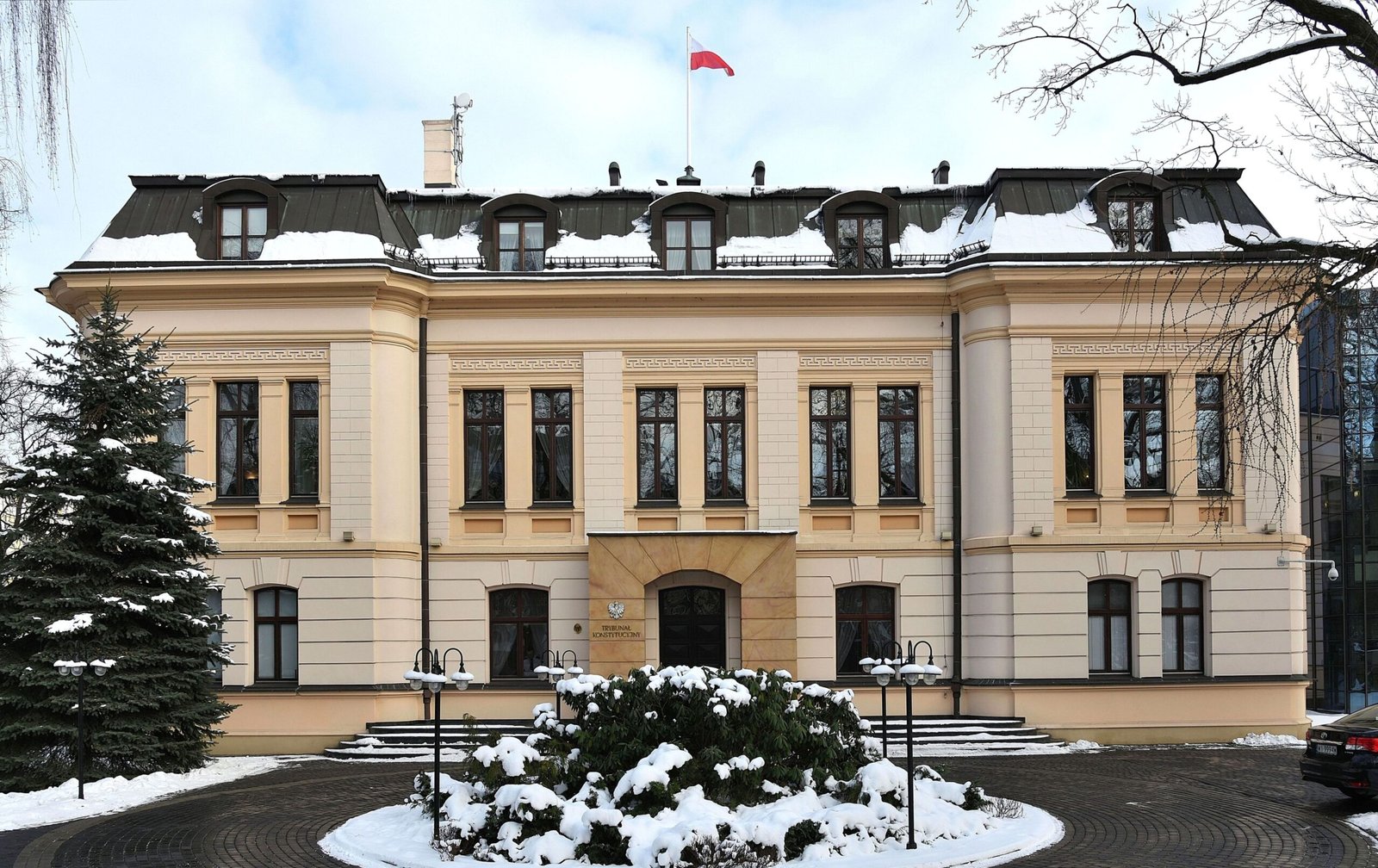 Fachada do prédio do Tribunal Constitucional da Polônia, em Varsóvia, com neve e a bandeira polonesa no alto