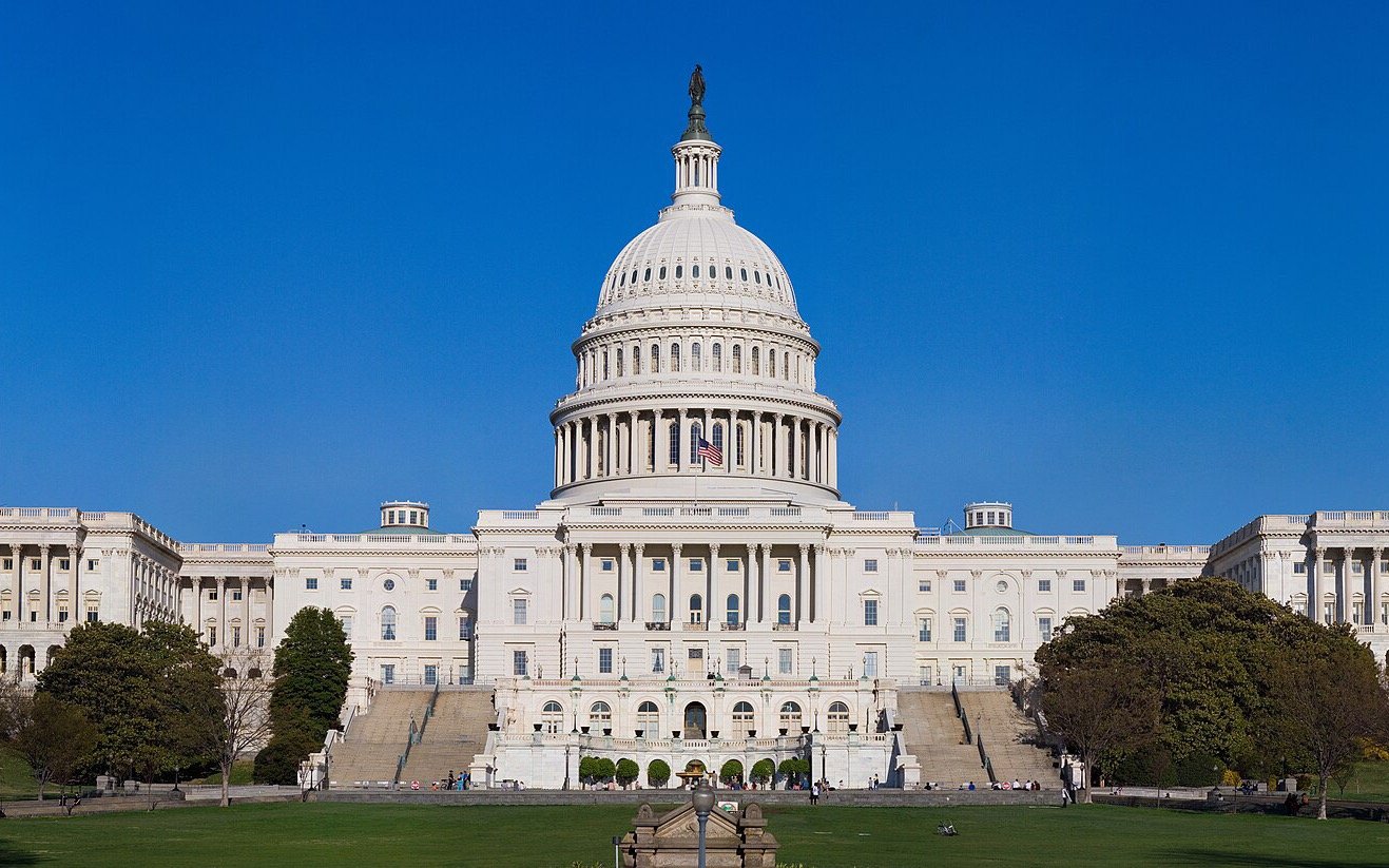 Fachada oeste do Capitólio dos Estados Unidos, em Washington, sob céu azul, com a cúpula ao centro