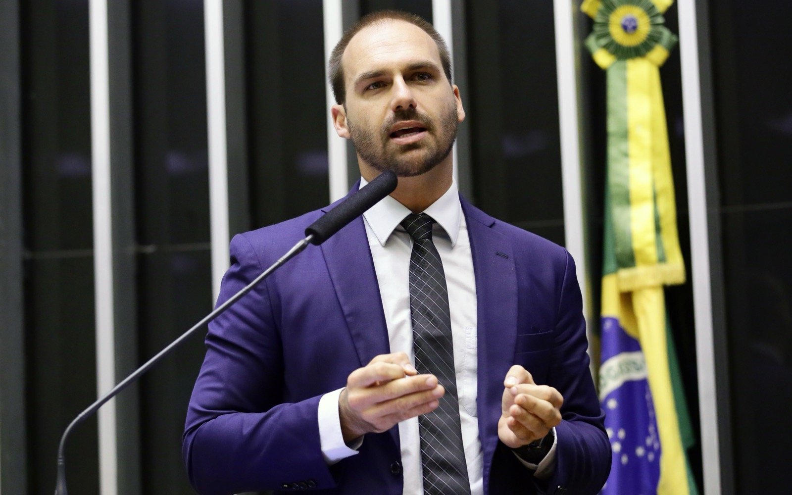 Eduardo Bolsonaro, de terno azul e gravata, fala ao microfone no plenário da Câmara dos Deputados