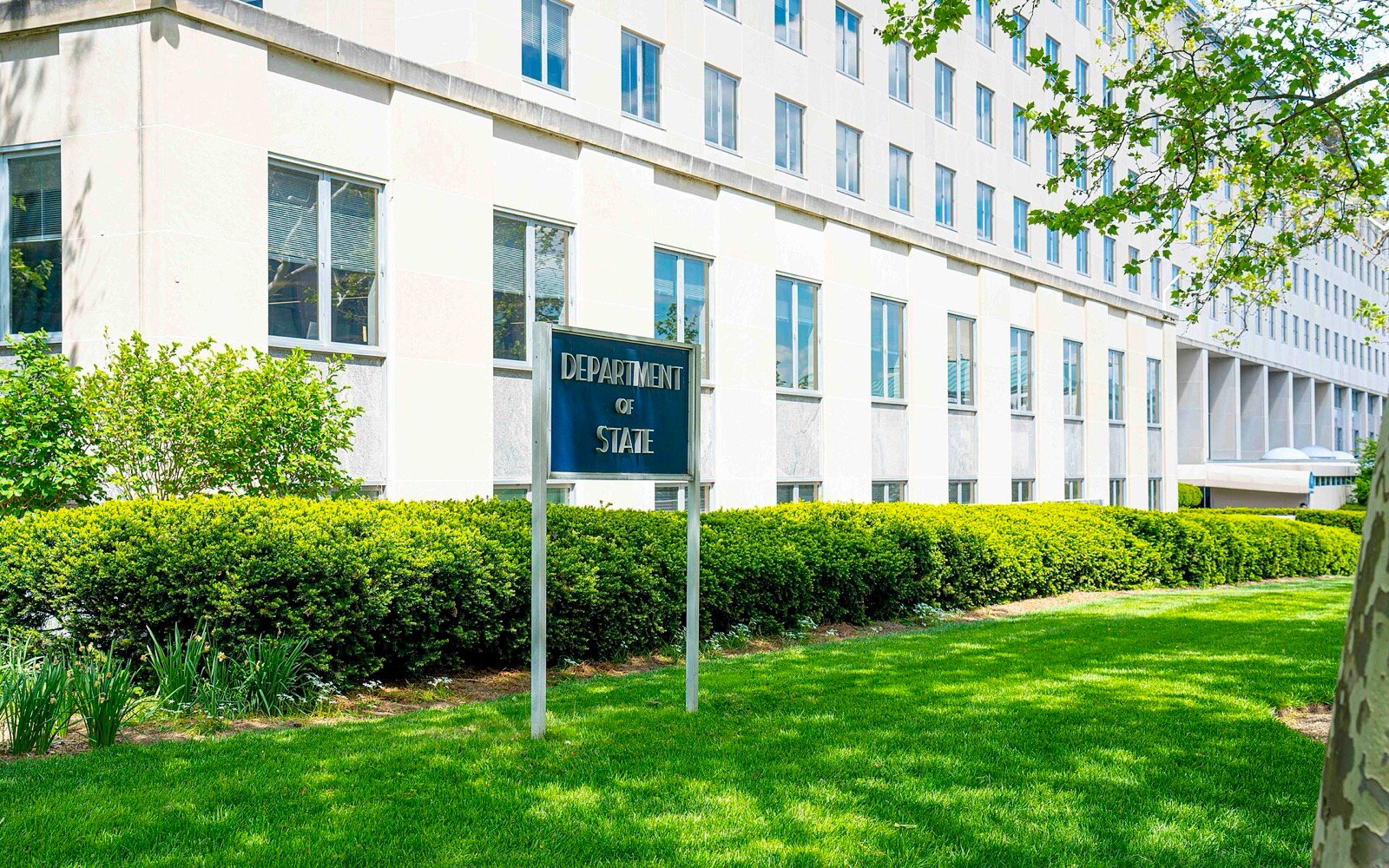 Fachada do edifício Harry S. Truman, sede do Departamento de Estado dos Estados Unidos, com a placa Department of State e um gramado em primeiro plano.
