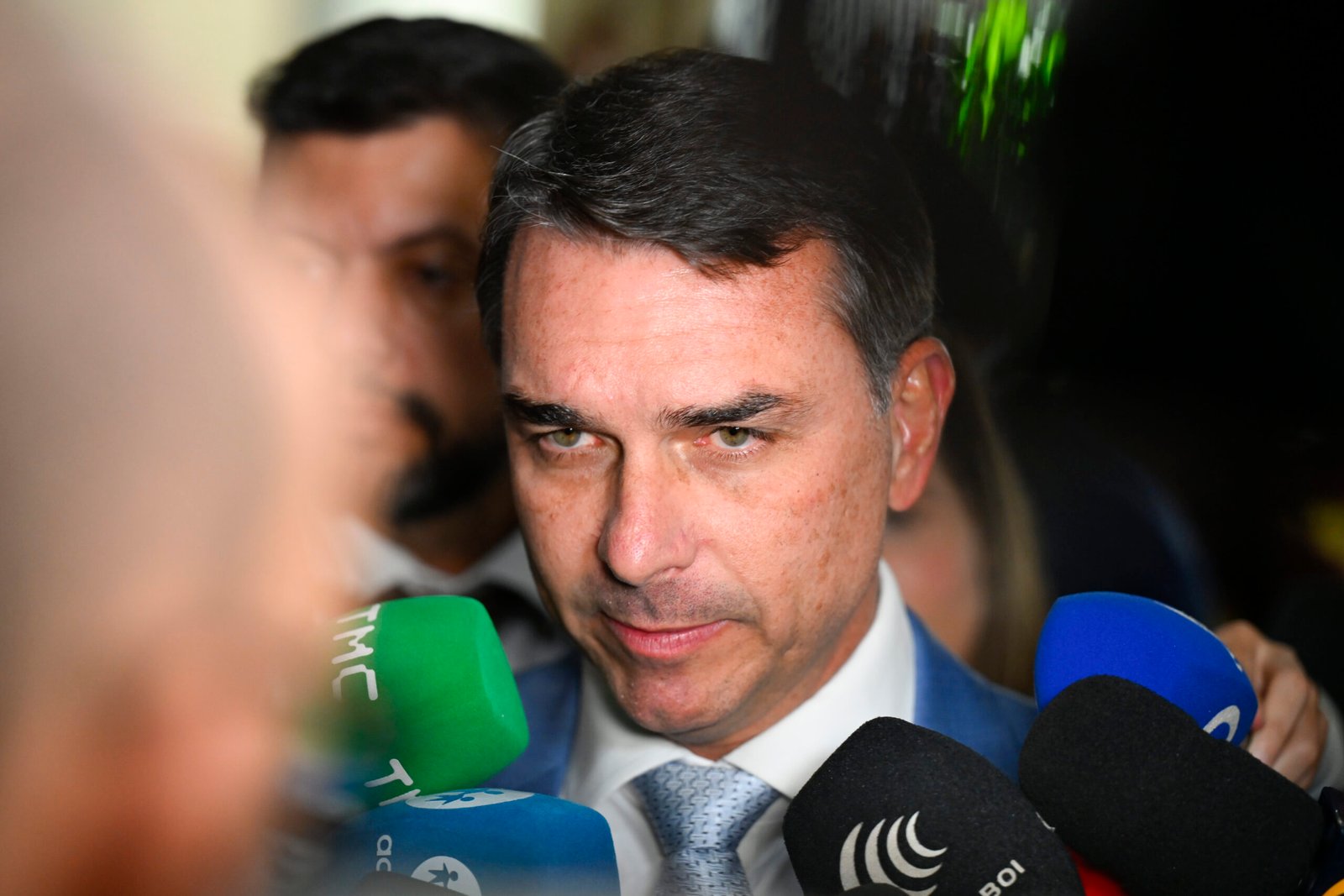 O senador Flávio Bolsonaro cercado por microfones durante entrevista no Senado Federal.