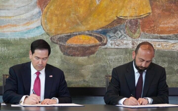 Marco Rubio, de terno escuro e gravata vermelha, assina um documento ao lado do chanceler armênio Ararat Mirzoyan