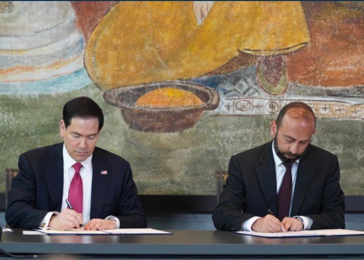 Marco Rubio, de terno escuro e gravata vermelha, assina um documento ao lado do chanceler armênio Ararat Mirzoyan