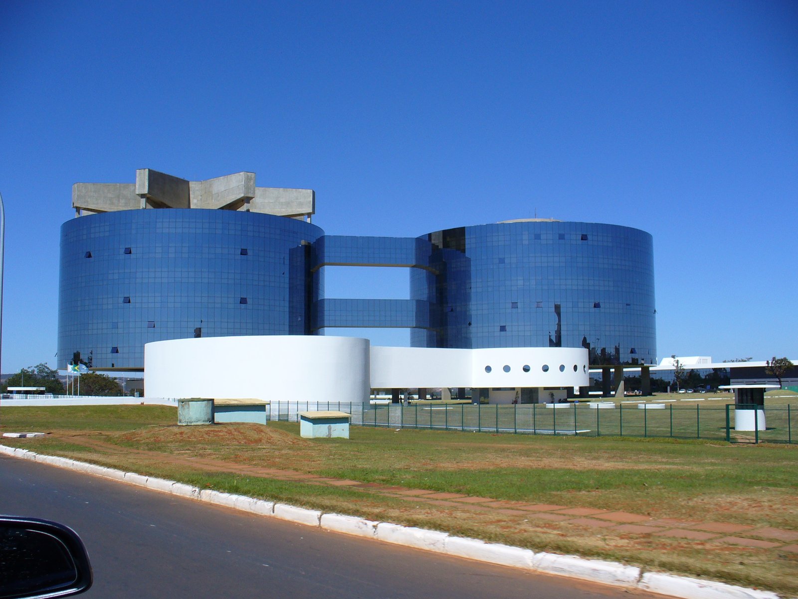 Prédios cilíndricos espelhados da sede da Procuradoria-Geral da República, em Brasília, vistos de uma avenida.