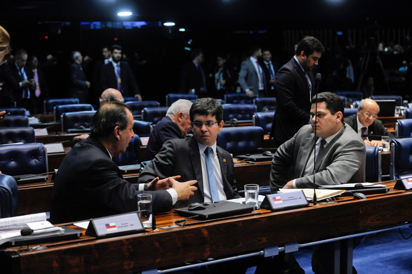 Senadores conversam em suas bancadas no plenário do Senado; à esquerda, Omar Aziz