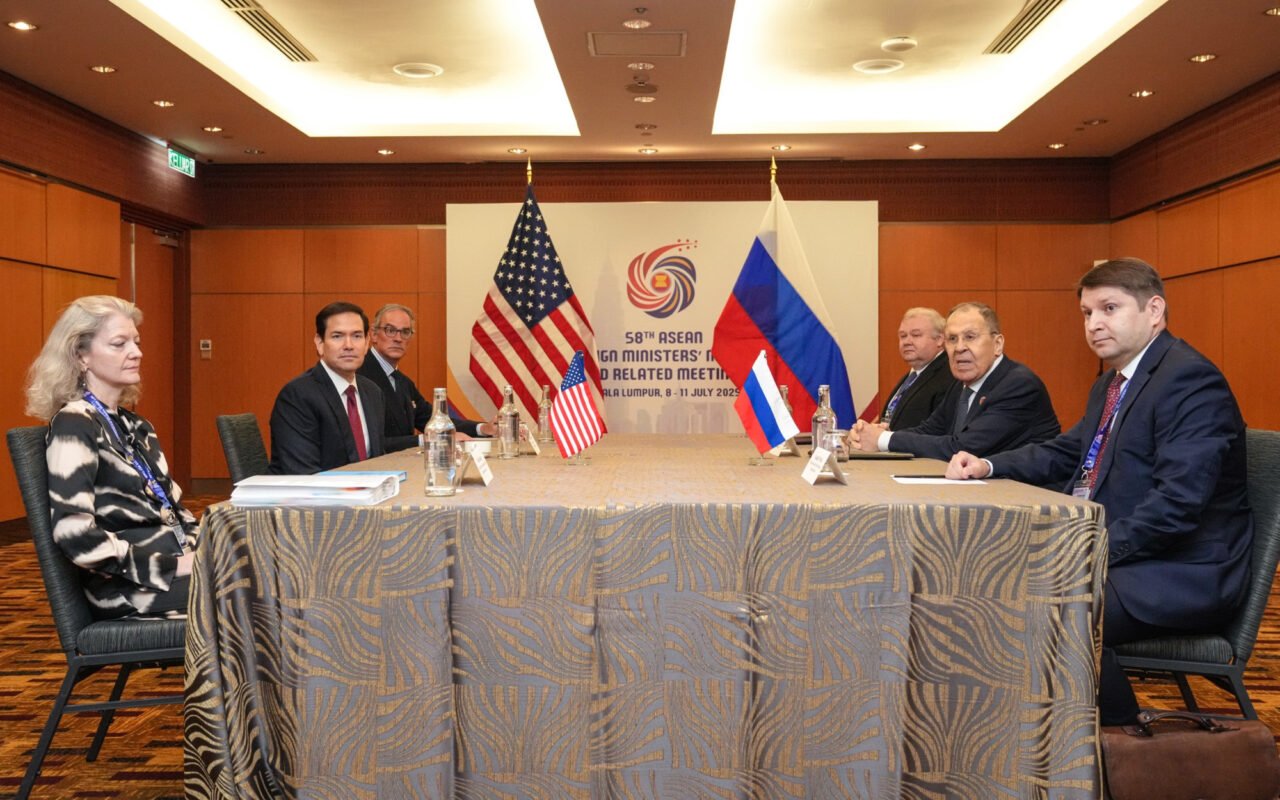 Secretário de Estado Marco Rubio e o chanceler russo Serguei Lavrov, cada um com sua delegação, sentados em lados opostos de uma mesa, com bandeiras dos EUA e da Rússia