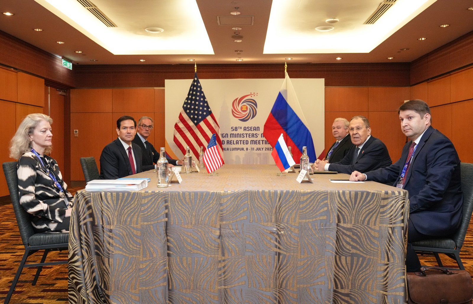 Secretário de Estado Marco Rubio e o chanceler russo Serguei Lavrov, cada um com sua delegação, sentados em lados opostos de uma mesa, com bandeiras dos EUA e da Rússia