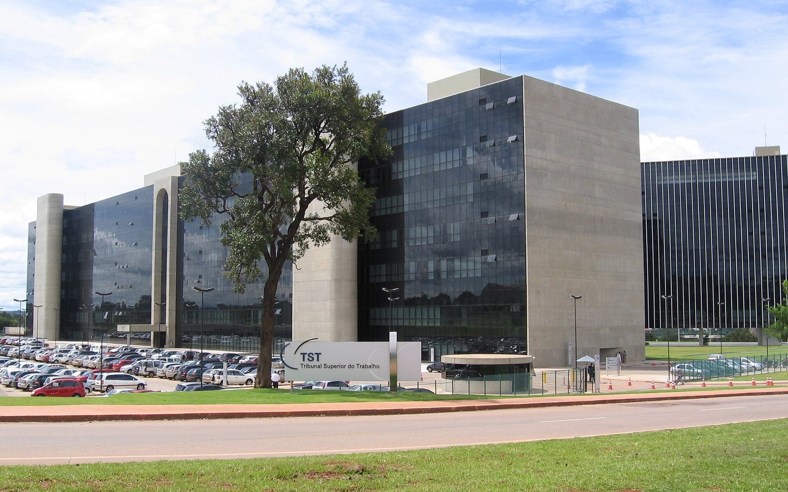 Fachada de vidro e concreto do edifício do Tribunal Superior do Trabalho, em Brasília, com a placa da instituição em primeiro plano