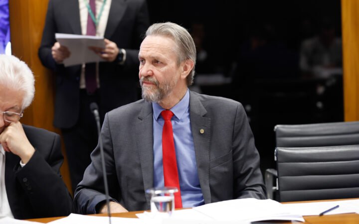 O deputado Pedro Uczai (PT-SC), de terno cinza e gravata vermelha, sentado a uma mesa em reunião de líderes na Câmara.